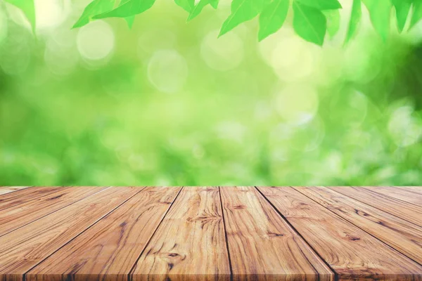 Lege houten terras tafelblad op groen wazig abstracte achtergrond van gebladerte achtergrond. Klaar gebruikt ons beeldscherm of montage ontwerp van de producten — Stockfoto