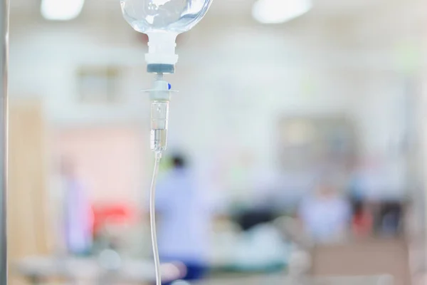 Medical saline iv drip close up with infusion pump in hospital, Saline intravenious on blurred doctor give medical and other attention to a sick person — Stock Photo, Image