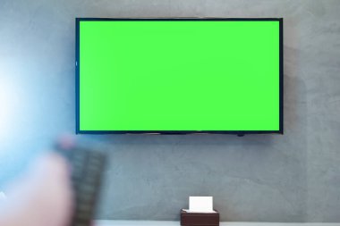 Yeşil ekran kompozisyon ile LED ekran Tv. TV ya da televizyon - uzaktan kumandanın bulanık el ile modern odasında duvarda yeşil ekran