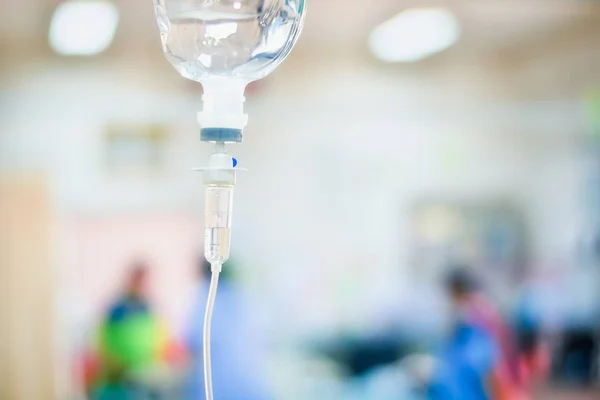 Close up saline IV drip for patient in hospital with copy space on n blurred doctor give medical and other attention to a sick person — Stock Photo, Image