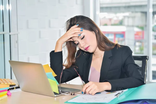 Stresset forretningskvinne sitter og holder hodet på grunn av smerte hodepine i moderne kontor – stockfoto