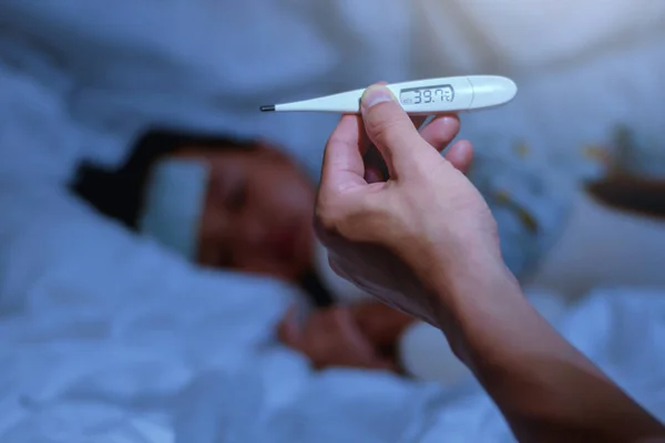 Father holding thermometer foreground of sick little girl in bedroom at night time for monitor high fever with thermometer for ,Kid had high fever and tepid sponging to bring the temperature down — Stock Photo, Image
