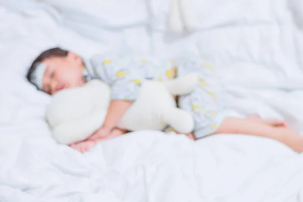 Bulanık küçük kız antipiretik için baş kullanımı bir kucaklama oyuncak ayı ve serin jel ile beyaz yatakta uyku ateş azaltır — Stok fotoğraf