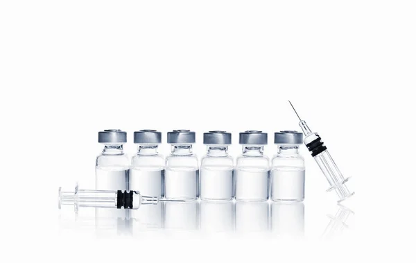 Rij van flesjes met medicatie en spuit met naald voor injectie op witte achtergrond — Stockfoto
