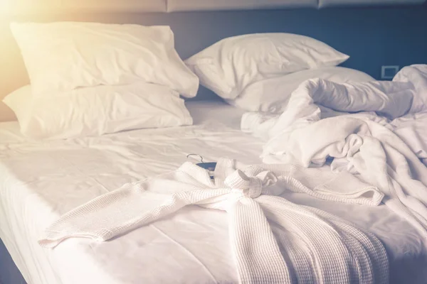 지저분한 침구 시트와 침실에 지저분한 주름이있는 이불로 깨어난 후 편안한 침실에서 침대에 목욕 가운 — 스톡 사진