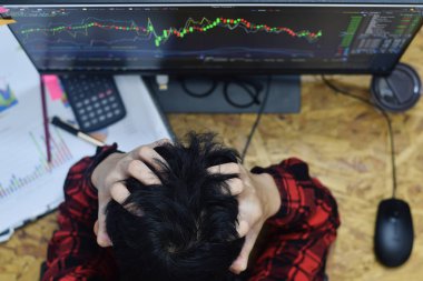 Stres nedeniyle başını tutarak yorgunluk adam elleri ve ev ofisinde bir baş ağrısı sahip iken Ticaret Forex veya hisse senedi Pazar online yatırım gece zaman