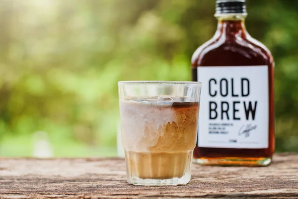 Kaltgebrühter Kaffee mit Milch auf einem Tisch draußen mit kaltgebrühtem Kaffee in einer Glasflasche zum Mitnehmen — Stockfoto