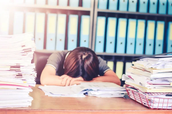 Suddig affärskvinna sover på skrivbordet på kontoret skrivbord med f pappersarbete stack dokument och ekonomi blad koncept för överarbetad eller hård arbetsbelastning. — Stockfoto