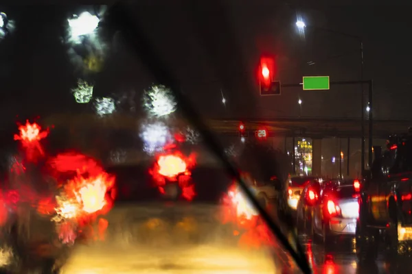 Um limpador de pára-brisas limpando a gota de chuva sobre o vidro do carro chuva pesada, dirigindo carro na estrada em engarrafamento na estação chuvosa — Fotografia de Stock