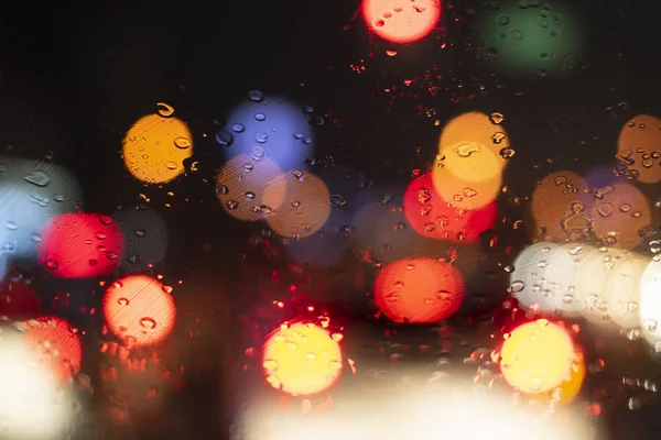 Uzavřete čelní sklo dešťové deště s bokehem semaforu, jízda autem na silnici v dopravní zácpě v deštivé sezóně — Stock fotografie