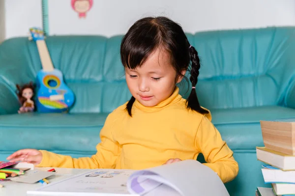 School Home work concept,Asian children wearing yellow casual clothing doing school home work drawing in Living room during the COVID-19 quarantine. Coronavirus isolation. online studying from home.