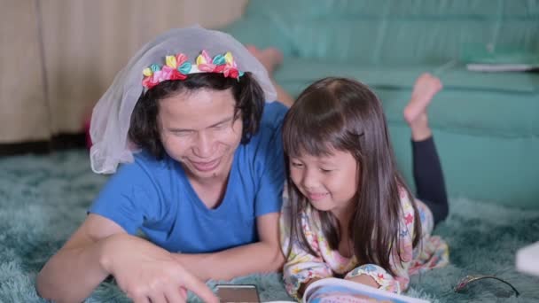 Aziatische vader man brengt tijd door met zijn kleine schattige dochter. Het lezen van sprookjes terwijl dochter ligt in de woonkamer voordat klaar om te slapen in de slaapkamer — Stockvideo