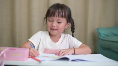 Asyalı küçük kız ev ödevi yapıyor. Resim çiziyor, resim yapıyor.