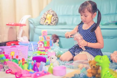 Child little girl play toys disorderly mess in living room a dirty or untidy state of toy and doll at home.