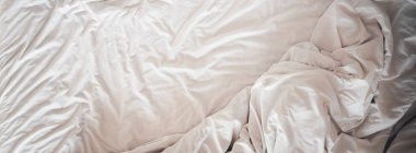 Yumuşak yatak çarşafları ve battaniyenin üst görüntüsü gece uykusundan sonra dağılmış, otel odasında rahat bir uyku, konsept seyahat ve geniş bir arka plan için tatil.