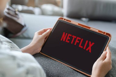 iPad 'de Netflix izleyen kadın, tablet ekranda Netflix uygulaması. Netflix, televizyon bölümleri ve filmleri için uluslararası bir abonelik servisidir: LOEI, THAILAND, 20 Haziran 2020.