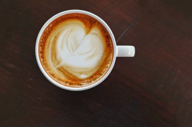 Sıcak kahve kapuçinosu ya da kahve, kahve, kahve fincanı üzerinde kırpma yolu olan ahşap masa..