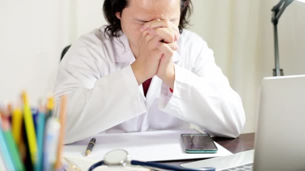 Stress médecin assis au bureau du médecin à l'hôpital, son désespéré tient sa tête mal de tête ou prier — Video