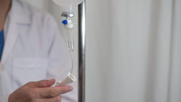 Close up soro fisiológico IV gotejamento Médico de infusão ajustado taxa de volume de frasco de fluido intravenoso com solução IV para paciente em hospital de enfermaria — Vídeo de Stock