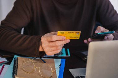 Merkez ofisteki akıllı telefondan kredi kartıyla ödeme yapan adam. Alışveriş, bankacılık, ev ve yaşam tarzı kavramı.