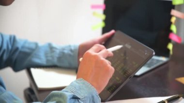 İşadamı hisse senedi grafiği ve bankacılık kar grafiği analizi için tablet kullanır.