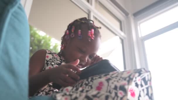 利用数字平板手表卡通片教育在线节目，坐在客厅沙发上的非洲儿童 — 图库视频影像