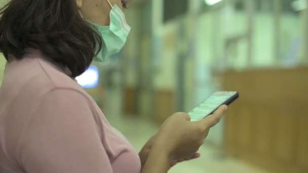 Wanita mengenakan masker wajah bedah dan menggunakan media sosial smartphone atau mencari berita tentang pandemi coronavirus — Stok Video