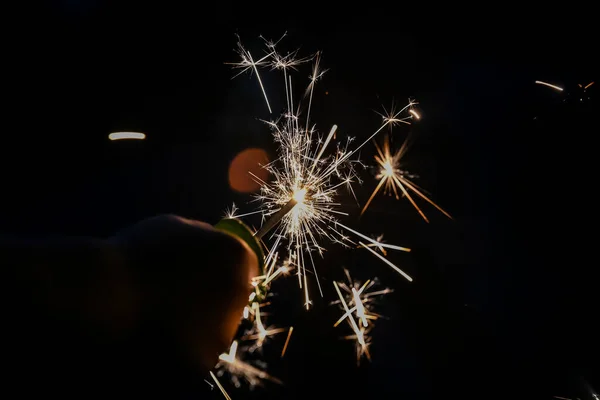 Рука держит фейерверк с открытой текстурой во время празднования ночи — стоковое фото