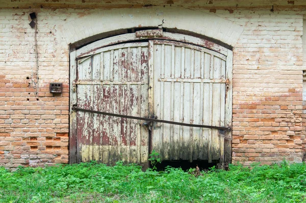 Paslı çift kapılı eski model tuğla duvar.