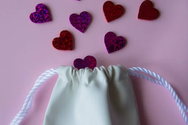 Piccola borsa in pelle bianca e sfondo rosa con cuori vista dall'alto. Il giorno di S. Valentino. biglietto di auguri — Foto Stock