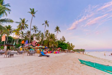 Alona Beach, Panglao, Bohol, Filipinler: Nisan 2017 - Açık hava barları ve restoranlarla dolu sahilde öğleden sonra sahnesi ve kıyıda yürüyen turistler.