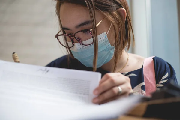 外科用マスクをしたアジア系女性が印刷物に署名している 新常態概念 — ストック写真