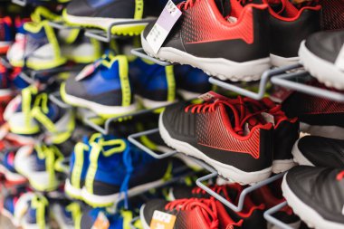 Shoes of varying colors, sizes and designs on display in a sport store. clipart
