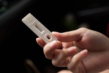 COVID-19 IgG ve IgM Antikor Testi negatif sonuç verdi. Kan lekesi olan test kitini tutan bir kadın el..