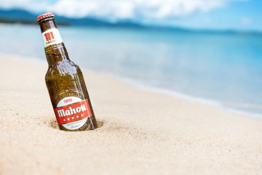 Bir şişe Tiger Crystal Light Birası kısmen tropik bir plajın yakınındaki kuma gömülebilir..
