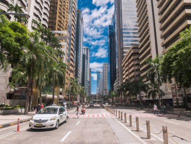 Ortigas, Metro Manila, Filipinler - Temmuz 2020: Yüksek gökdelenlerle çevrili Ortigas CBD 'deki tipik cadde manzarası. Yolun sol tarafına park etmiş bir taksi..