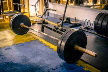 Plastik kaplamayla dolu paslı olimpik bir halter. Kaldırma pozisyonu alındı. sert tema ve ayar.