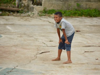 Bohol, Filipinler - Haziran 2019: Gülümseyen çıplak ayaklı bir çocuk köy basketbol sahasındaki arkadaşlarıyla kovalamaca oynarken nefesini tutuyor.