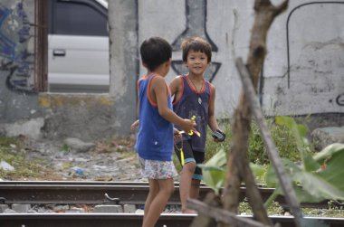 San Andres Bukid, Makati, Filipinler - Haziran 2019: Zavallı bir çocuk trenin geçtiği demiryolu kenarında oynarken kameramanı fark eder. Metro Manila 'da aşırı yoksulluk.