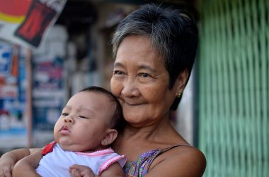 San Andres Bukid, Makati, Filipinler - Aralık 2018: Yoksul bir bölgede torunuyla umut dolu ve gülümseyen bir büyükanne. Filipinler 'deki olumluluğun ve aile bağlarının sembolü..