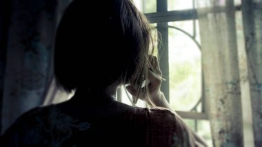Evdeki pencereye bakan bir kadının silueti korkunç bir çağrı alıyor. Sıkıntı, kayıp ya da üzüntü konsepti.