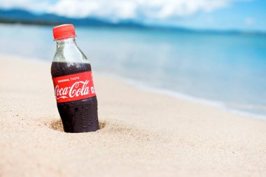 Filipinler - Eylül 2019: Bir PET Coca Cola şişesi kısmen kumsalda gömülü.