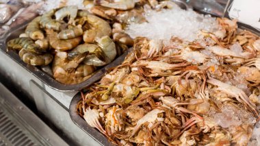 Sulu karidesler ve bebek yengeçler süpermarketin ya da marketin deniz ürünleri bölümünde sergileniyor..