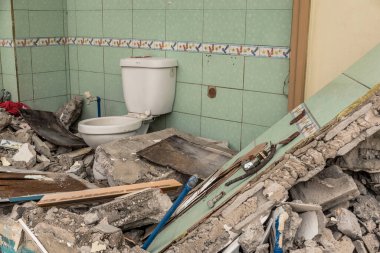 Yıkık bir banyo, bir duvar ve tuvalet hala sağlam. Yıkımı, savaş sahnesini ya da depremi temsil edebilir..