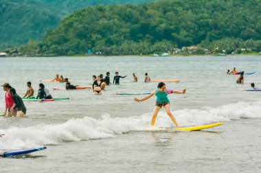 Baler, Aurora, Filipinler - Ağustos 2018: Bir Turist Sabang Sahilinde küçük dalgalarda sörf yapıyor.