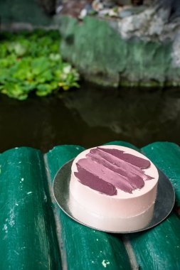 Koi havuzunun yanındaki sahte bambu köprüsünün üzerine kırmızı kadife kaplı küçük minimalist bir pasta..