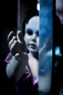 Bir odanın sürgülü kapısının içinden eline ulaşan ürkütücü bir bebek. Korku ya da rahatsız edici kavram.