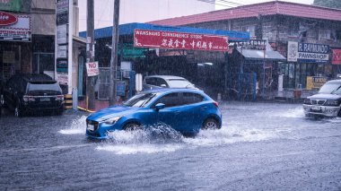 Metro Manila, Filipinler - Ağustos 2020: Şiddetli sağanak yağış nedeniyle sel basmış sokaklarda mavi bir Mazda sabanı sürüyor.