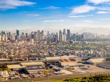Makati ve Ortigas Skylines 2020 'den itibaren uçaktan görüldü. Havaalanı hangarları ön planda görünüyor.