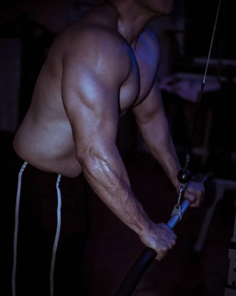 一个匿名的赤身裸体男子用机器俯冲训练他的三头肌 密集训练 蓝色灯光下的黑暗设置 运动半小时后汗流浃背 — 图库照片